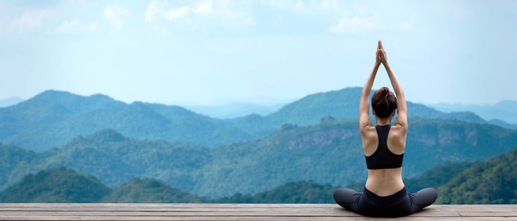 An image of a person meditating with their eyes closed, surrounded by greenery and natural scenery. This image represents the power of mind-body practices in improving brain health and cognitive function.