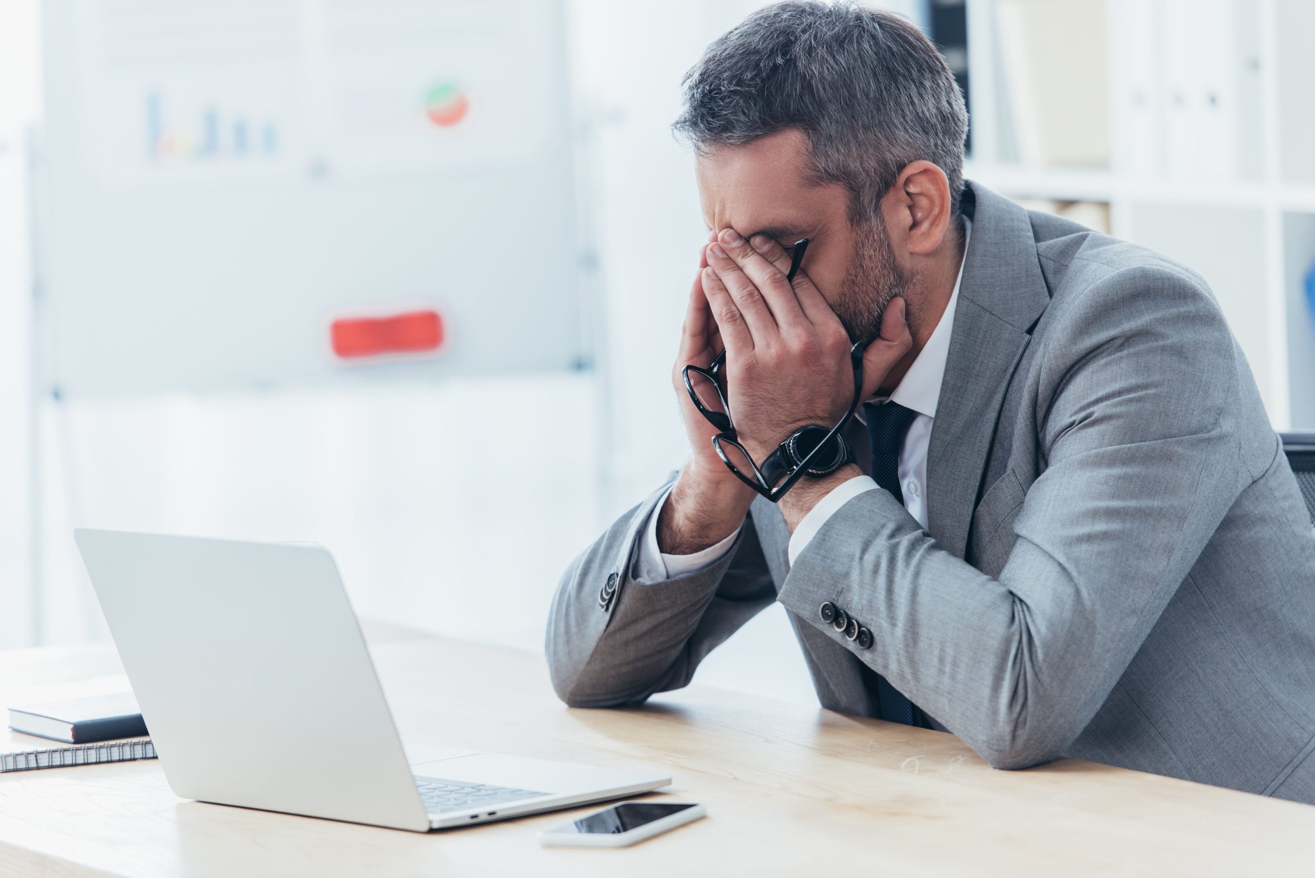 Frustrated man sitting at a laptop struggling to refocus after losing concentration